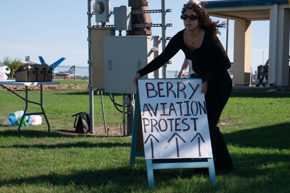 Sam Benavides, the communications director for Mano Amiga, sets up a sign outside of Berry Aviation's facilities. San Marcos City Council Member Alyssa Garza, who is a member of Mano Amiga, called for the council to consider terminating Berry Aviation's lease agreements with the city.