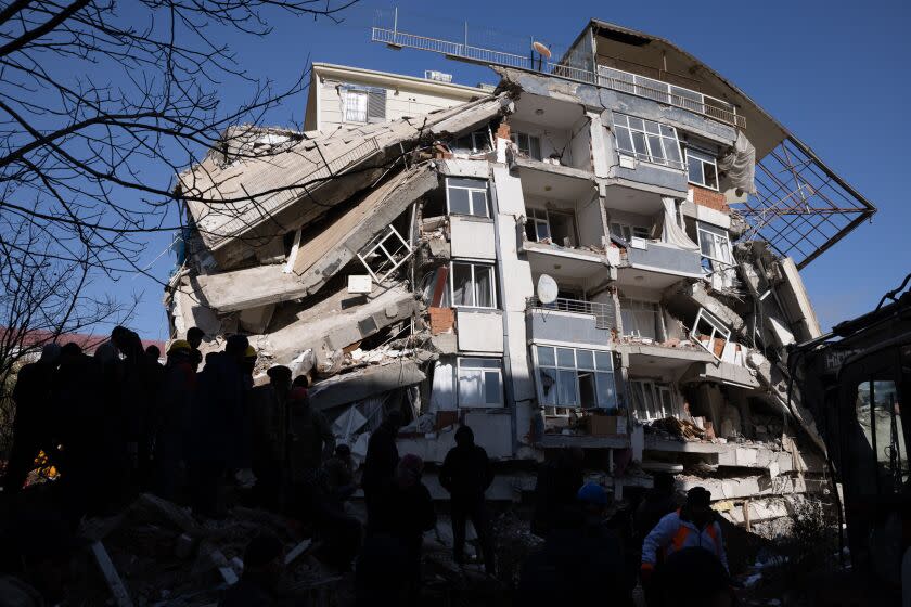 Silhouetted people are seen in the foreground of badly damaged building