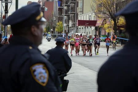 Runners from the woman's elite division run as New York City Police Department officers watch in the Williamsburg section of the borough of Brooklyn during the New York City Marathon in New York, November 3, 2013. REUTERS/Shannon Stapleton