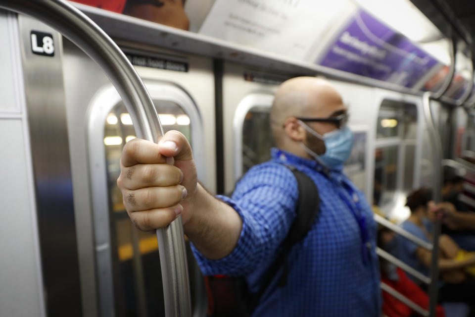 Joseph Ortiz, a contact tracer with New York City's Health + Hospitals battling the coronavirus pandemic, takes the subway system on the way to a potential patient's home Thursday, Aug. 6, 2020, in New York. The city has hired more than 3,000 tracers and the city says it's now meeting its goal of reaching about 90% of all newly diagnosed people and completing interviews with 75%. (AP Photo/John Minchillo)