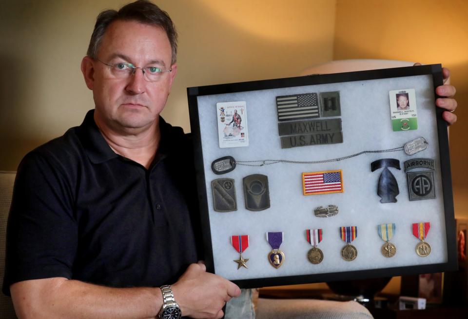 Afghanistan combat veteran Austin Maxwell holds up some of his military items that he received after serving with the US Army National Guard, including a Purple Heart, in his Murfreesboro home on Wednesday, Aug. 17, 2021. Maxwell is concerned about the Afghan people as the Taliban takes over the country and the United States removes their troops. 