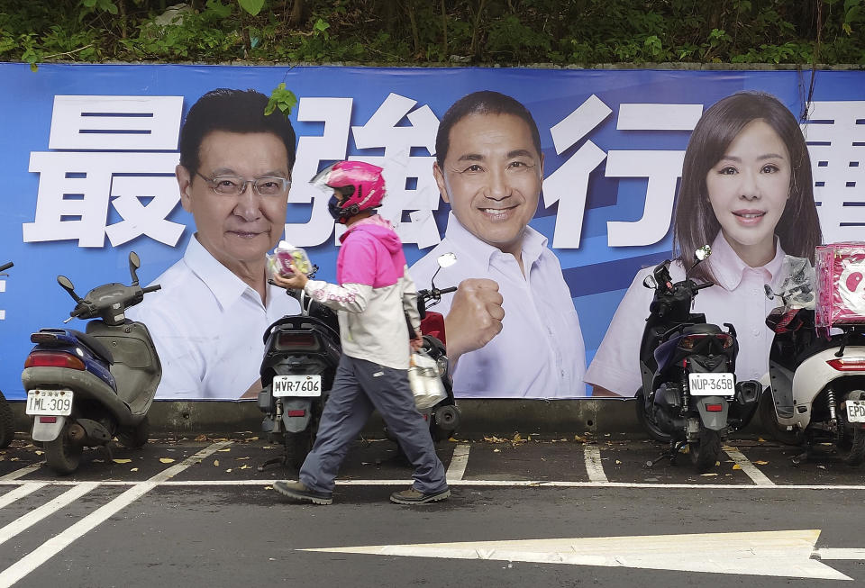 People pass by a poster of candidates running for the Taiwanese presidential election in Taipei, Taiwan, Saturday, Dec. 30, 2023. Taiwan will hold its presidential election on Jan. 13, 2024. (AP Photo/Chiang Ying-ying)