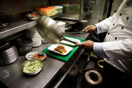 Abdul Ahad, owner of the City Spice curry house, serves a vegan meal in the kitchen of his restaurant on Brick Lane in London, Britain January 7, 2019. Picture taken January 7, 2019. REUTERS/Simon Dawson