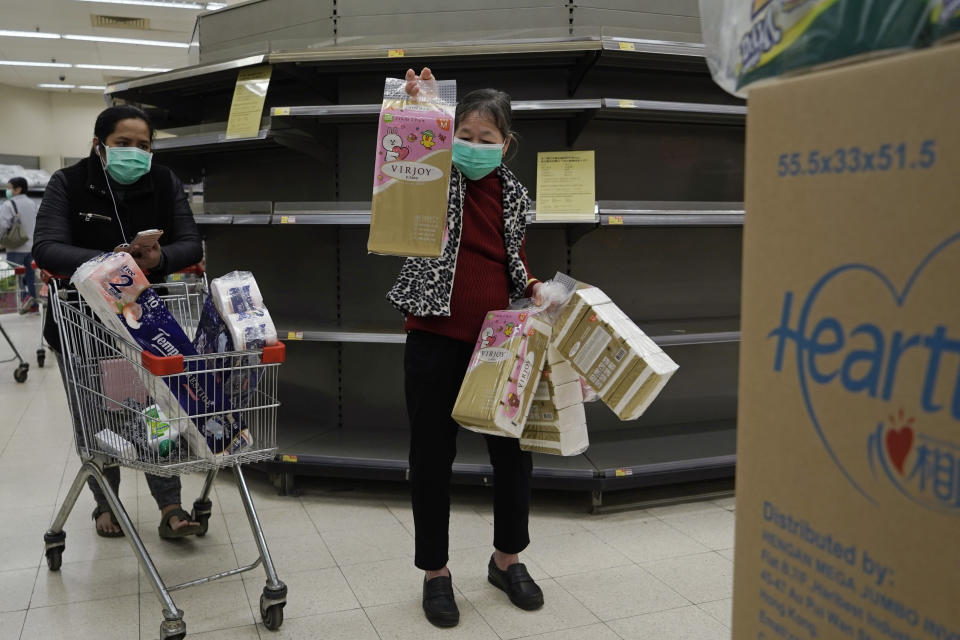 Customers wearing masks, purchase tissue papers in front of the empty shelf in a supermarket in Hong Kong, Saturday, Feb. 8, 2020. Widespread panic-buying of essentials such as toilet rolls and rice has hit in Hong Kong, a knock-on effect of the virus outbreak in mainland China. (AP Photo/Kin Cheung)