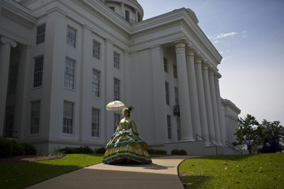 FILE - United Daughters of the Confederacy member Carrie McGough walks in front of the Alabama Capitol building during a confederate memorial day ceremony in Montgomery, Ala., on Monday, April 27, 2015. McGough said she designed and sewed her hoop skirt to look like an authentic Civil War era dress. (AP Photo/Brynn Anderson, File)