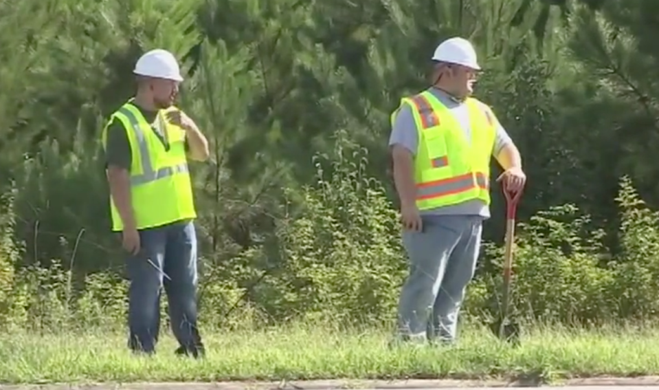 Undercover Atlanta police officers are seen posing as construction workers in high-visibility vests and hard hats at the side of the road.