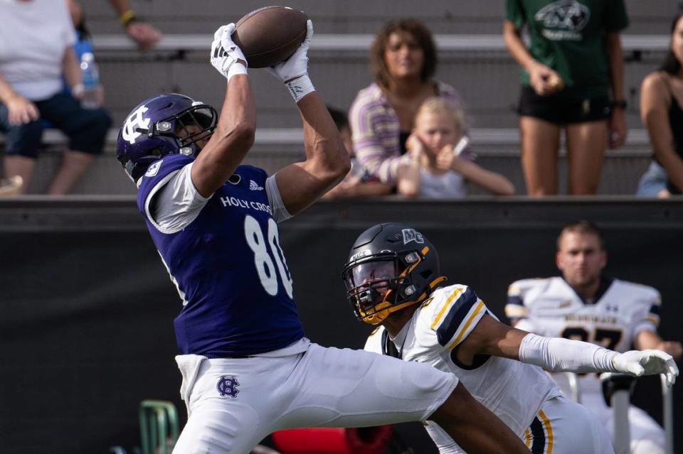 Holy Cross’s Jalen Coker hauls in a pass for a first down over Merrimack’s Darion McKenzie in 2023.