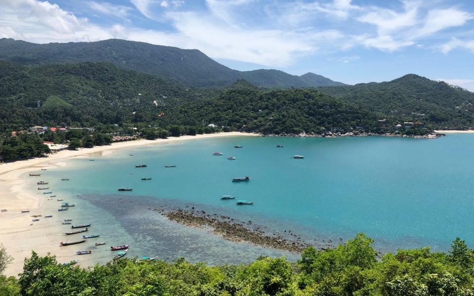 Fishing vessels and boats used to ferry tourists sit idle along a deserted beach on the popular tourist island of Koh Phangan, Thailand - AP