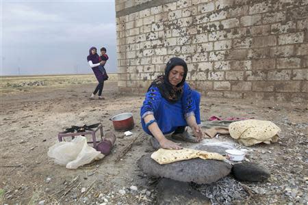 A woman makes bread near Al-Yaroubia crossing in the province of Hassaka in this November 10, 2013 file photo. REUTERS/Stringer/Files