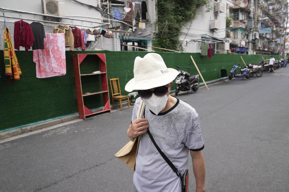 A resident wearing a mask walks past barriers around a community Thursday, June 2, 2022, in Shanghai. Traffic, pedestrians and joggers reappeared on the streets of Shanghai on Wednesday as China's largest city began returning to normalcy amid the easing of a strict two-month COVID-19 lockdown that has drawn unusual protests over its heavy-handed implementation. (AP Photo/Ng Han Guan)