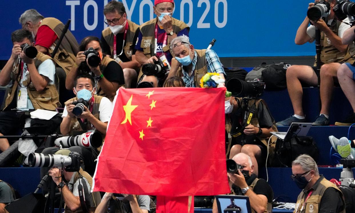 <span>A Chinese flag is unfurled on the podium of a swimming event at the 2020 Olympics in Tokyo.</span><span>Photograph: Charlie Riedel/AP</span>