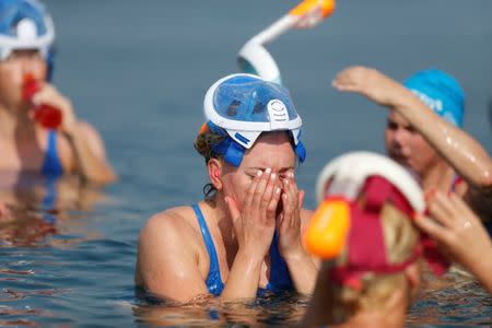 An environmental activist washes her face while taking part in "The Dead Sea Swim Challenge", swimming from the Jordanian to Israeli shore, to draw attention to the ecological threats facing the Dead Sea, in Kibbutz Ein Gedi, Israel November 15, 2016. REUTERS/Nir Elias