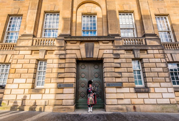 A bagpiper in front of the High Court of Justiciary in Edinburgh.