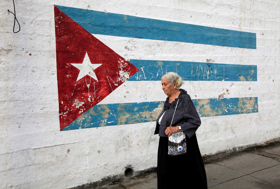 Woman walks past a mural of a Cuban flag in Havana