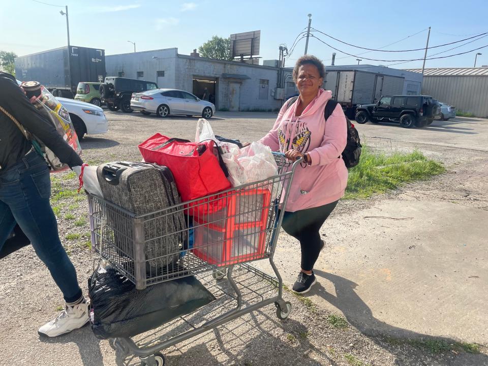 Robin Morris pushes a shopping cart containing her possessions, which include a suitcase, a trash bag with a tent inside and a plastic set of drawers.