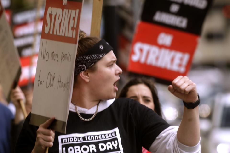 Sara Schunck yells and raises a fist while walking the picket line.