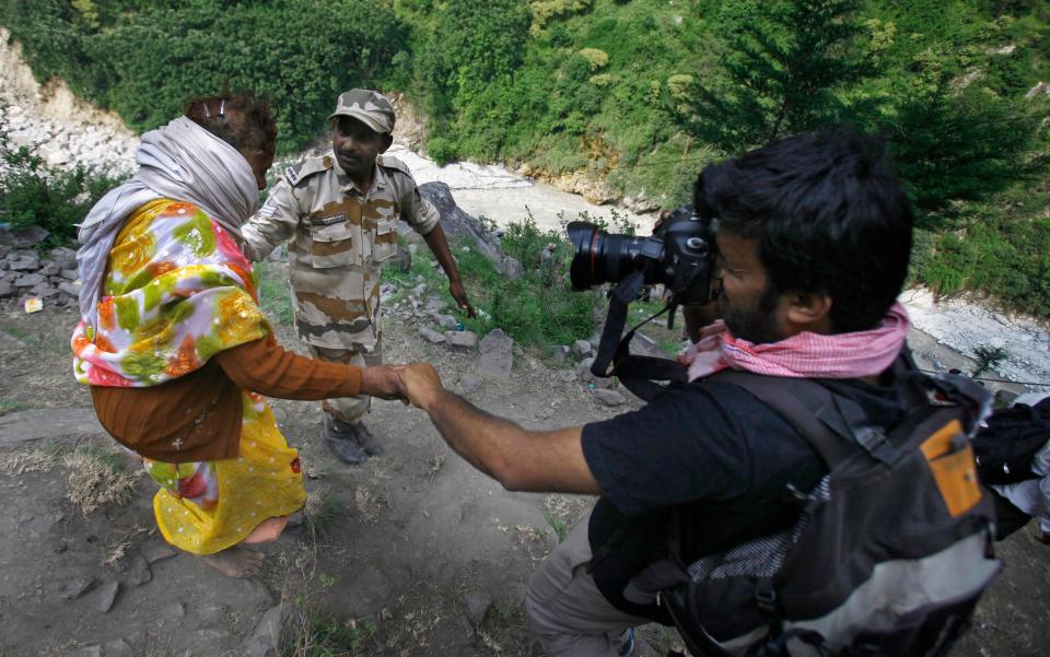 Siddiqui helps a flood victim at Govindghat in India in 2013 - Rafiq Maqbool/AP