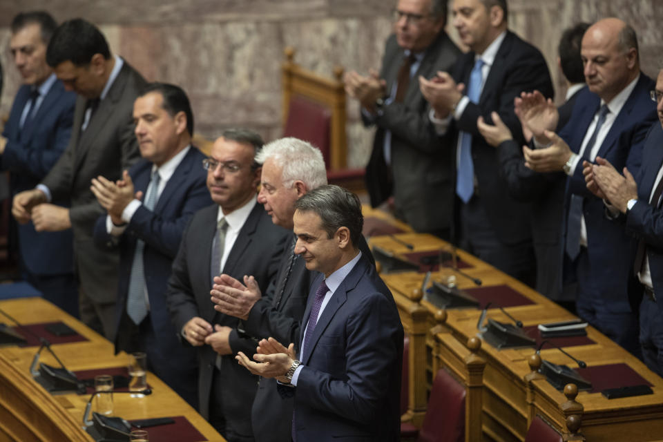 Greek Prime Minister kyriakos Mitsotakis, front, applauds with other members of the government during a parliamentary session to vote for the new Greek President, in Athens, on Wednesday, Jan. 22, 2019. High court judge Katerina Sakellaropoulou has been elected at Greece's first female president with an overwhelming majority in a parliamentary vote. (AP Photo/Petros Giannakouris)