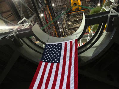 The American flag can be seen hanging from the final work platform, A north, as the platform is lifted up by crane from the transfer aisle in the Vehicle Assembly Building (VAB) at NASA's Kennedy Space Center in Florida. The platform will be installed and secured on its rail beam high up on the north wall of High Bay 3. The installation of the final topmost level completes the 10 levels of work platforms, 20 platform halves altogether, that will surround NASA's Space Launch System rocket and the Orion spacecraft and allow access during processing for missions, including the first uncrewed flight test of Orion atop the SLS rocket in 2018. The A-level platforms will provide access to the Orion spacecraft's Launch Abort System for Orion lifting sling removal and installation of the closeout panels. The Ground Systems Development and Operations Program, with support from the center's Engineering Directorate, is overseeing upgrades and modifications to the VAB, including installation of the new work platforms. 