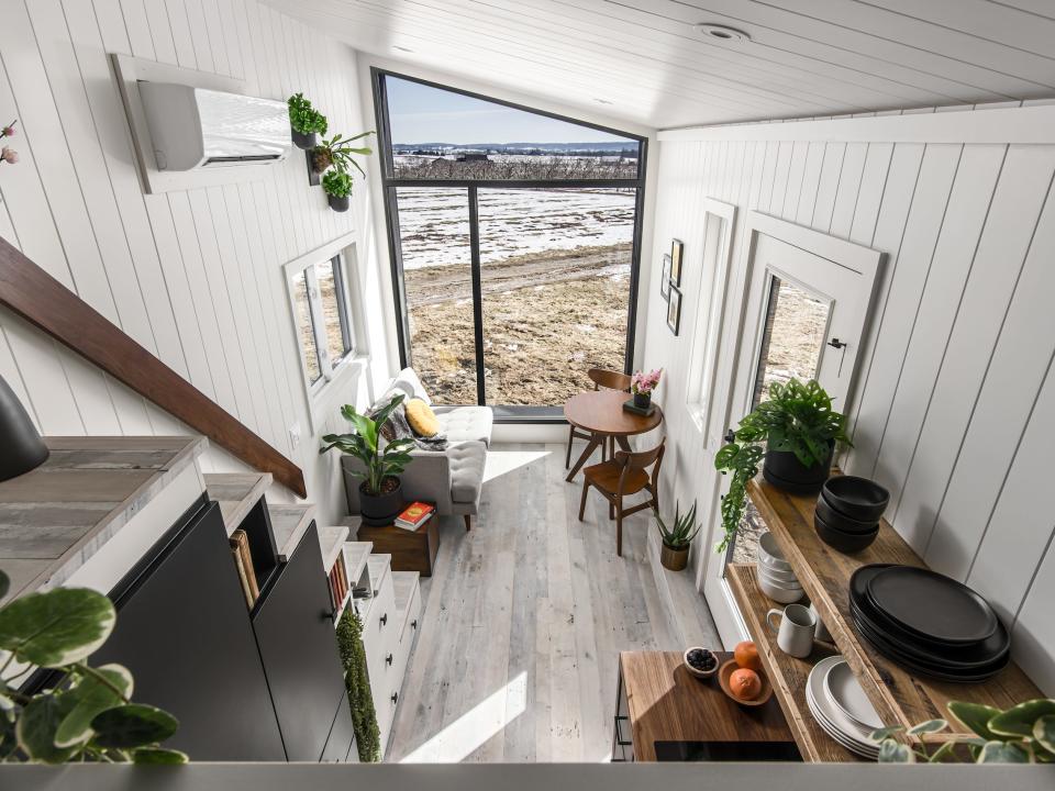 a birds eye view of the tiny home's living room and kitchen next to a large glass wall