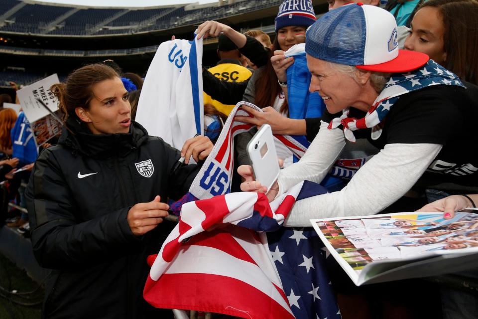 Tobin Heath (left) signs merchandise for fans after a 2016 USWNT match.