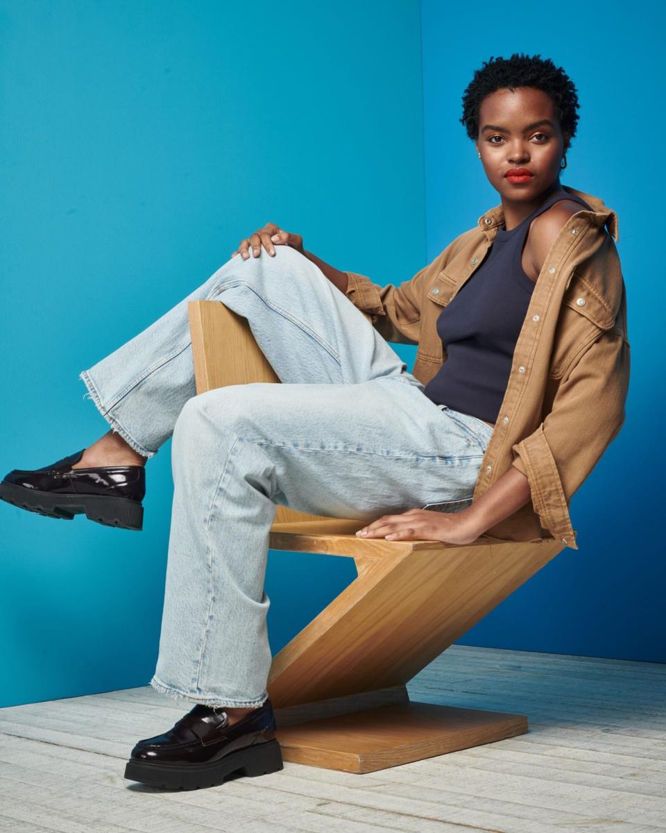 Woman sitting on a chair wearing denim with a blue background