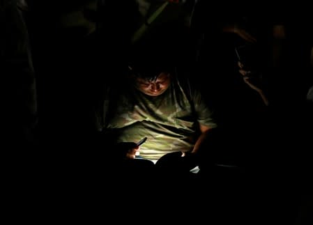 A Central American migrant reads a document outside his tent in an encampment in Matamoros