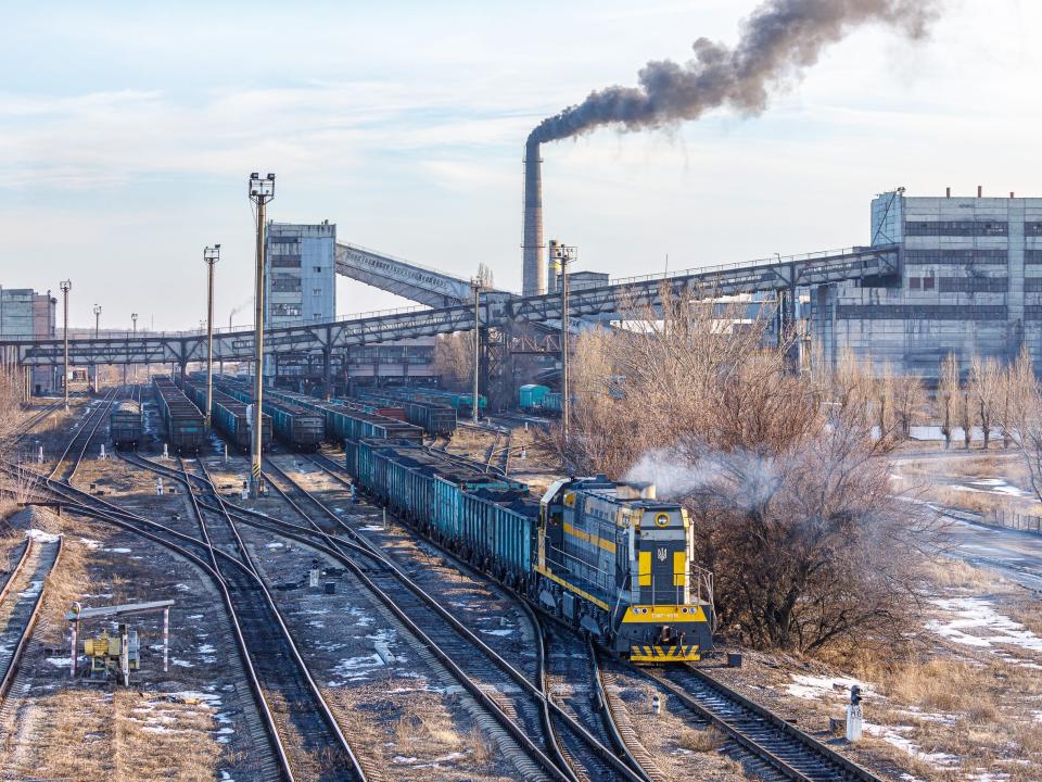 Mariupol, Ukraine - winter 2022: Powerful diesel locomotive TEM7 pulls wagons loaded with anthracite along a large coal mine station.