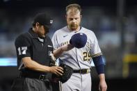 Umpire D.J. Reyburn (17) examines the glove and cap of Milwaukee Brewers starter Brett Anderson, right, as the pitcher leaves a baseball game due to injury during the second inning against the Arizona Diamondbacks, Monday, June 21, 2021, in Phoenix. Beginning Monday, Major League Baseball will enhance its enforcement of rules that prohibit applying foreign substances to baseballs. (AP Photo/Ross D. Franklin)