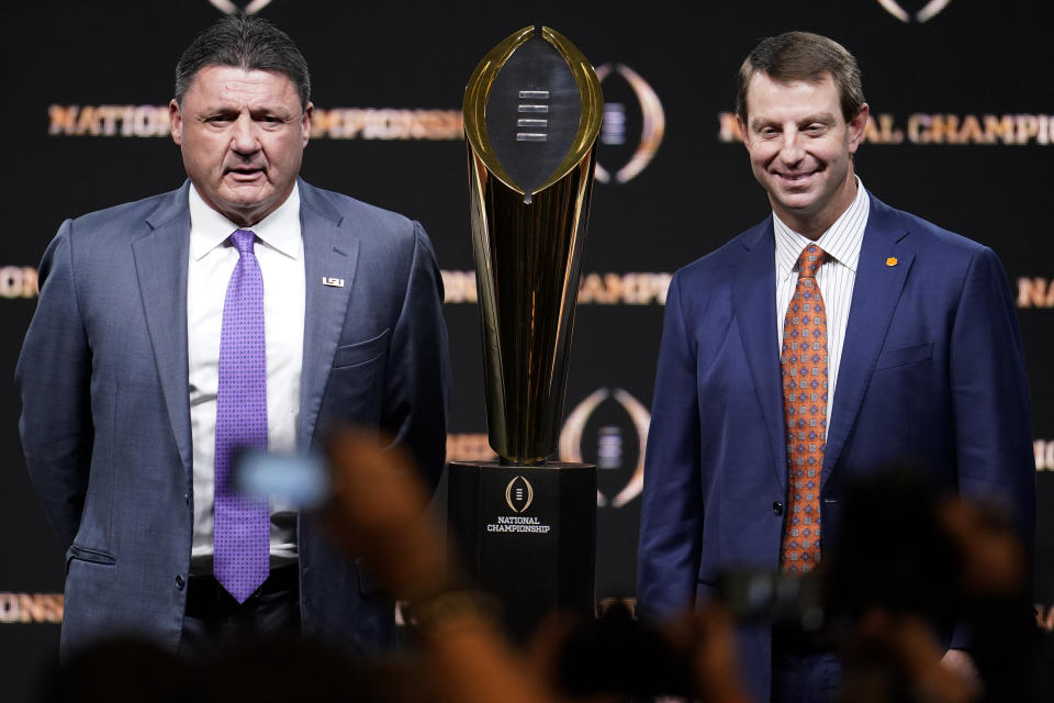 LSU head coach Ed Orgeron, left, and Clemson head coach Dabo Swinney pose with the trophy after a news conference for the NCAA College Football Playoff national championship game Sunday, Jan. 12, 2020, in New Orleans. Clemson is scheduled to play LSU on Monday. (AP Photo/Chris Carlson)