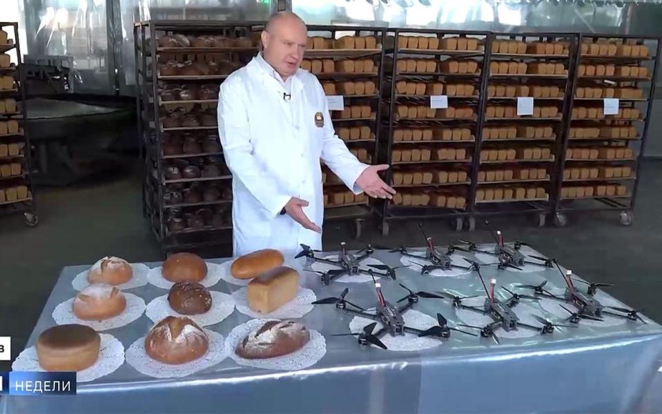 A man gestures to loaves of bread and drones