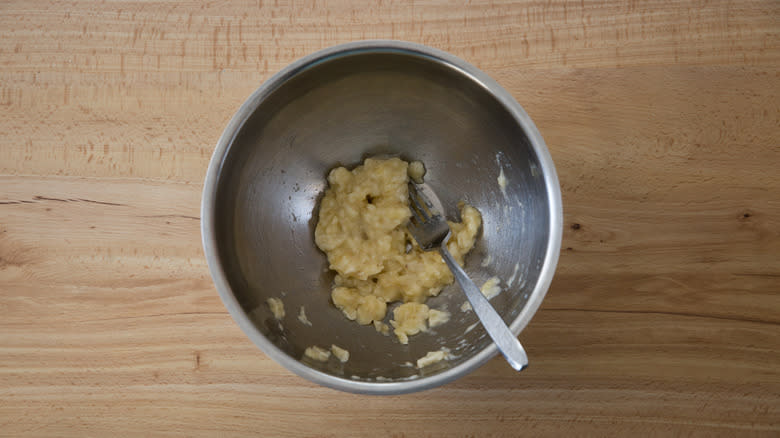 mashed banana in mixing bowl with fork