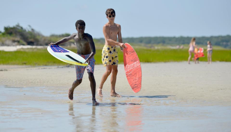 Ejan O'Connor, 14, of Maryland, left, and Michael Lysiak, 16, of New Jersey, take turns skimboarding on the flats off Skaket Beach in Orleans on Monday.