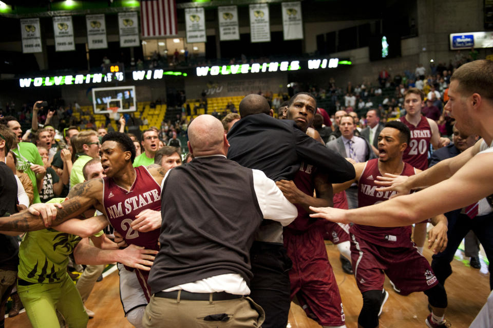 In this Thursday, Feb. 27, 2014 photo, security, at center back to camera, try to hold back players as a wild brawl involving players and fans who came onto the court broke out when New Mexico State guard K.C. Ross-Miller hurled the ball at Utah Valley's Holton Hunsaker seconds after the Wolverines' 66-61 overtime victory against the Aggies in Orem, Utah. (AP Photo/The Daily Herald, Grant Hindsley) MANDATORY CREDIT