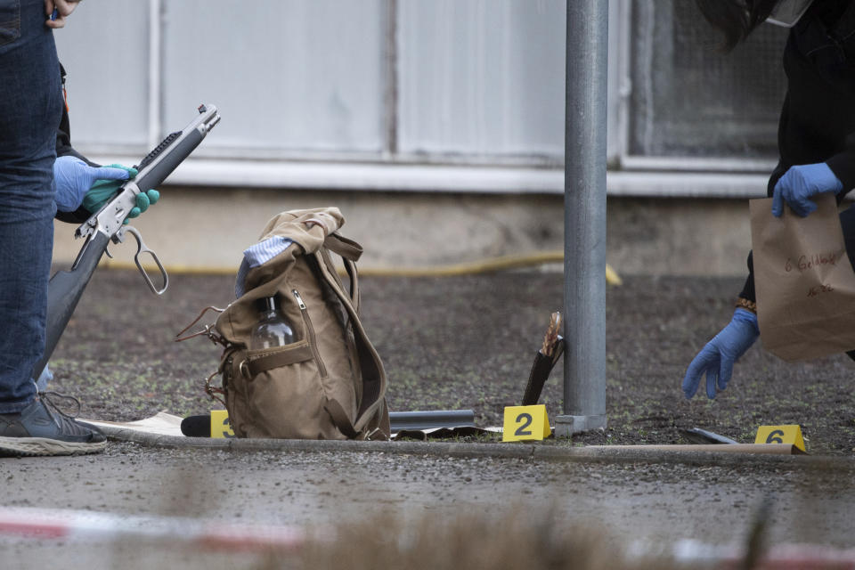 Police officers examine a gun and a purse on the campus of Heidelberg University, Germany, Monday, Jan. 24, 2022. German police say a lone gunman has wounded four people at a Heidelberg University lecture hall in southwestern Germany. Police said that the perpetrator was dead after Monday's incident, but didn’t give details of how that happened. (Sebastian Gollnow/dpa via AP)