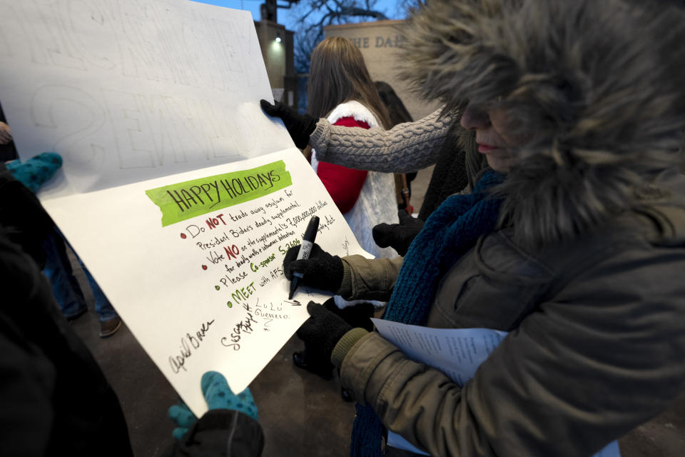 People sign a Christmas card to be delivered to U.S. Sen. John Hickenlooper, D-Colo., during a Posada celebration, Sunday, Dec. 17, 2023, in Fort Morgan, Colo. Organizers put on the Posada, a Latin-American tradition based on the religious events of Joseph and Mary searching for shelter before the birth of Jesus, as a way for migrants in Colorado to feel a sense of unity during the holiday season. (AP Photo/Julio Cortez)