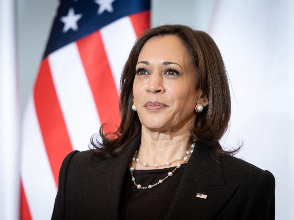 Kamala Harris stands in front of an American flag during a visit to Poland.