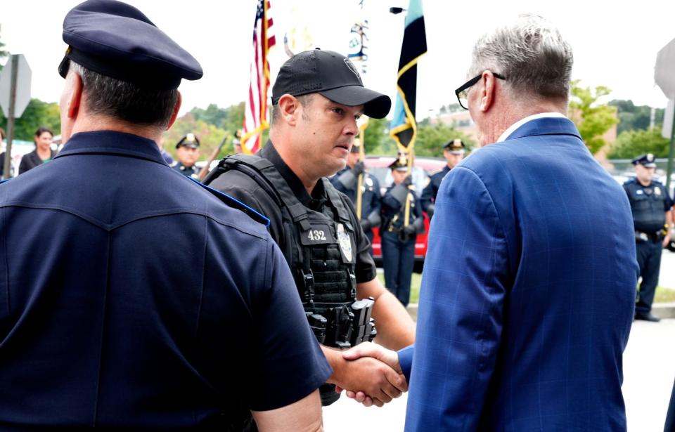 Cranston Officer Nathan Bagshaw shakes hands with Mayor Ken Hopkins during a "last call" ceremony for his K9 partner, Lex, at the Cranston police station Monday afternoon.