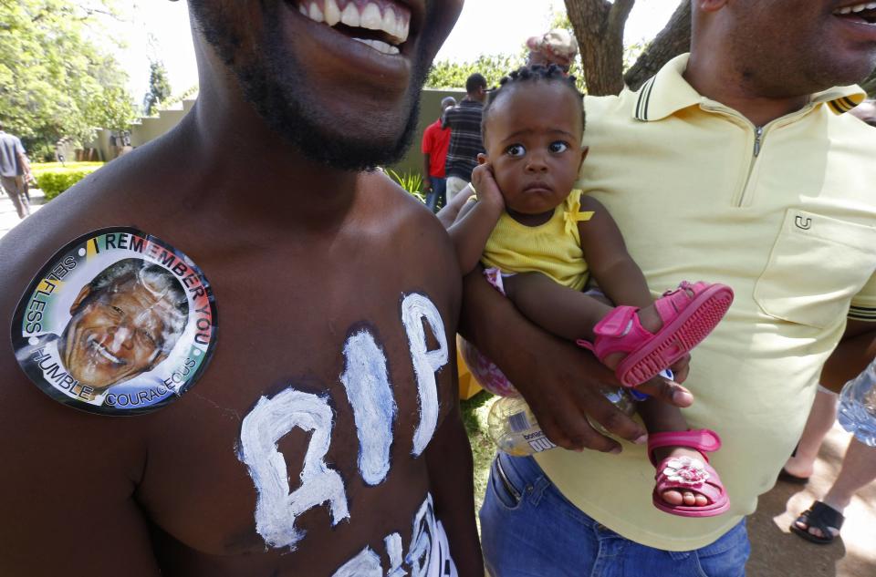 A child waits with her father in a bus line to pay their respects to former South African President Mandela in Pretoria