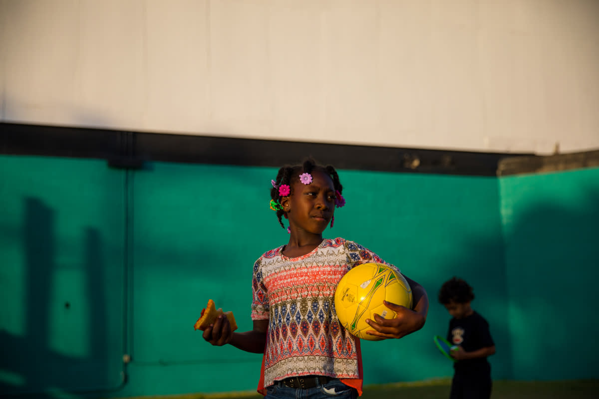 A little girl plays in the parking lot of a drive-in movie theater. 