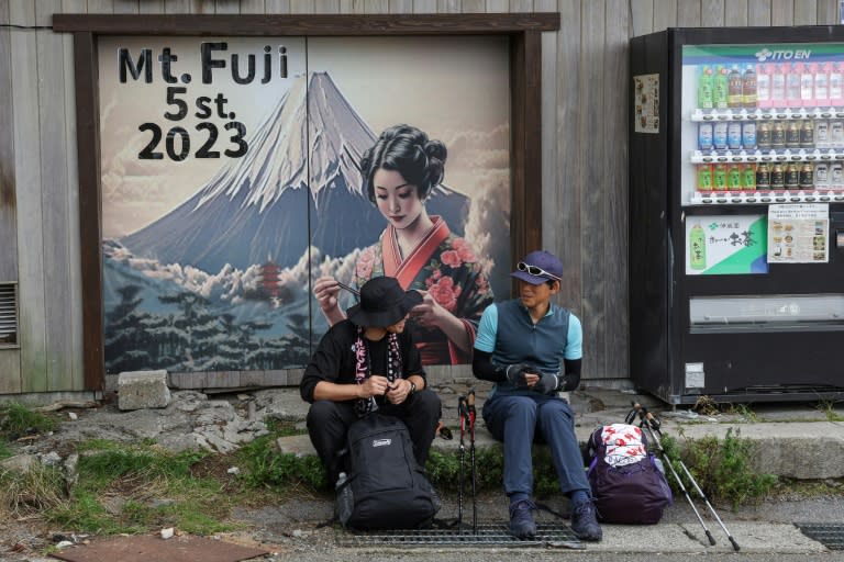 Dos excursionistas descansan al pie del sendero del monte Fuji, el más alto de Japón, el 31 de agosto de 2023 (Mathias CENA)