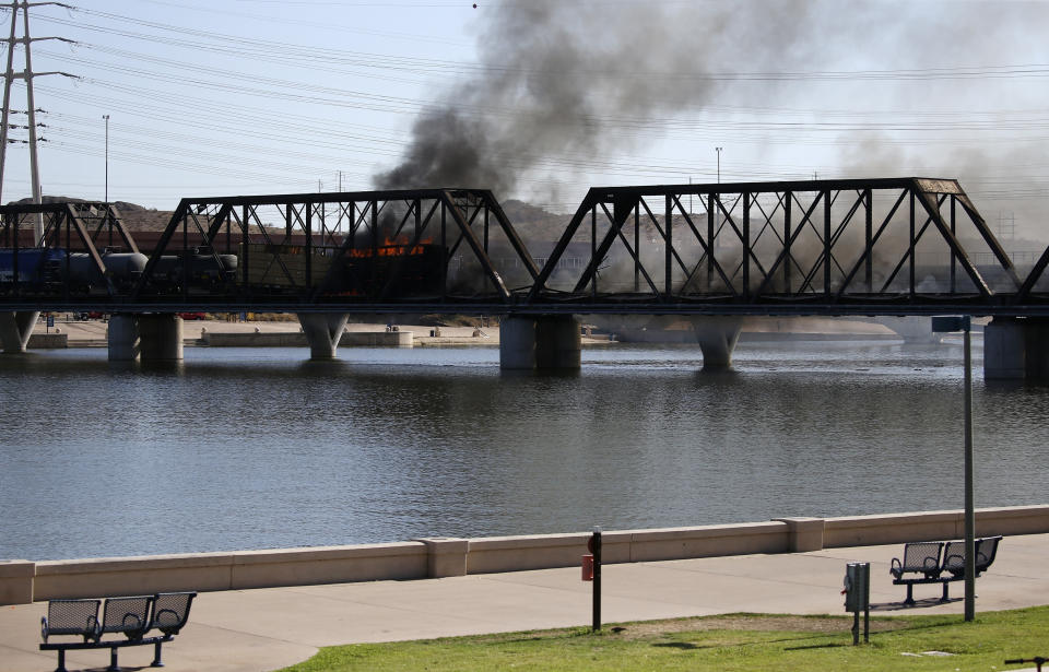 A derailed freight train burns on a bridge spanning Tempe Town Lake Wednesday, July 29, 2020, in Tempe, Ariz. Officials say a freight train traveling on the bridge that spans a lake in the Phoenix suburb has derailed, setting the bridge ablaze and partially collapsing the structure. (AP Photo/Ross D. Franklin)