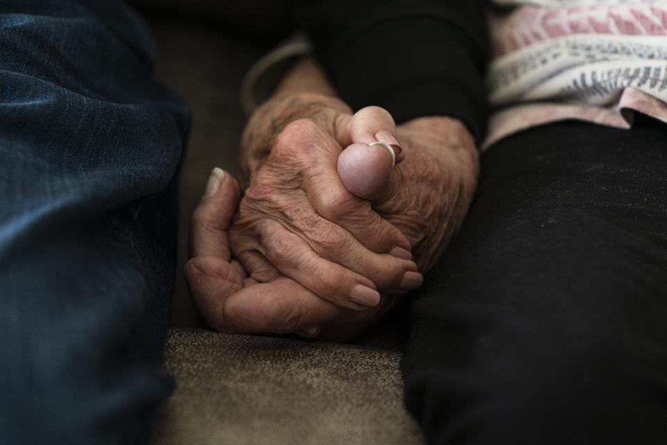 Norma Carr and Robert Carr hold hands at the home they are temporary staying at in Columbiana, Ohio, Wednesday, April 5, 2023. The two along with their family were displaced by the train derailment in East Palestine. Norma Carr said she raised four children in the cedar-sided 1930s duplex she moved into 57 years ago and where three generations lived together before the derailment. (AP Photo/Matt Rourke)