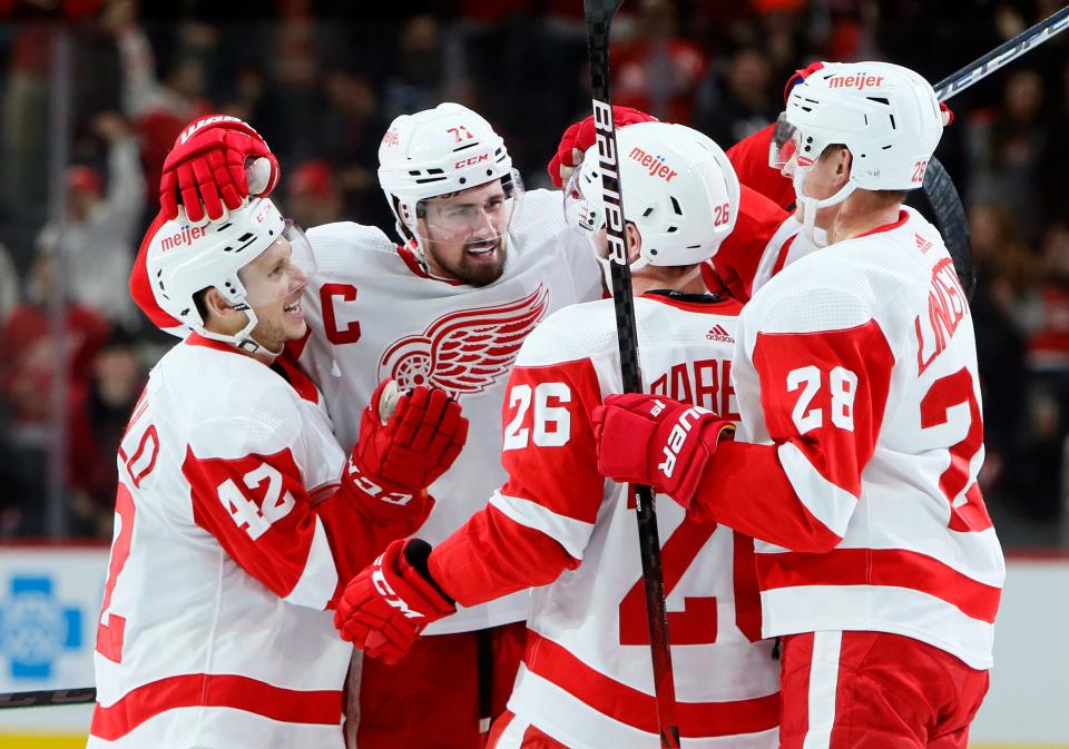 Red Wings center Dylan Larkin, second from left, celebrates with center Kyle Criscuolo (42), right wing Riley Barber (26) and defenseman Gustav Lindstrom (28) after scoring a hat trick against the Devils during the second period of the Wings' win on Saturday, Dec. 18, 2021, at Little Caesars Arena.