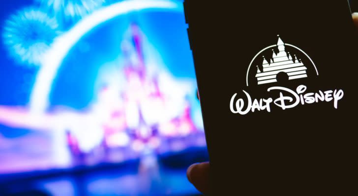 Walt Disney (DIS) logo on mobile phone with Cinderella's castile in background