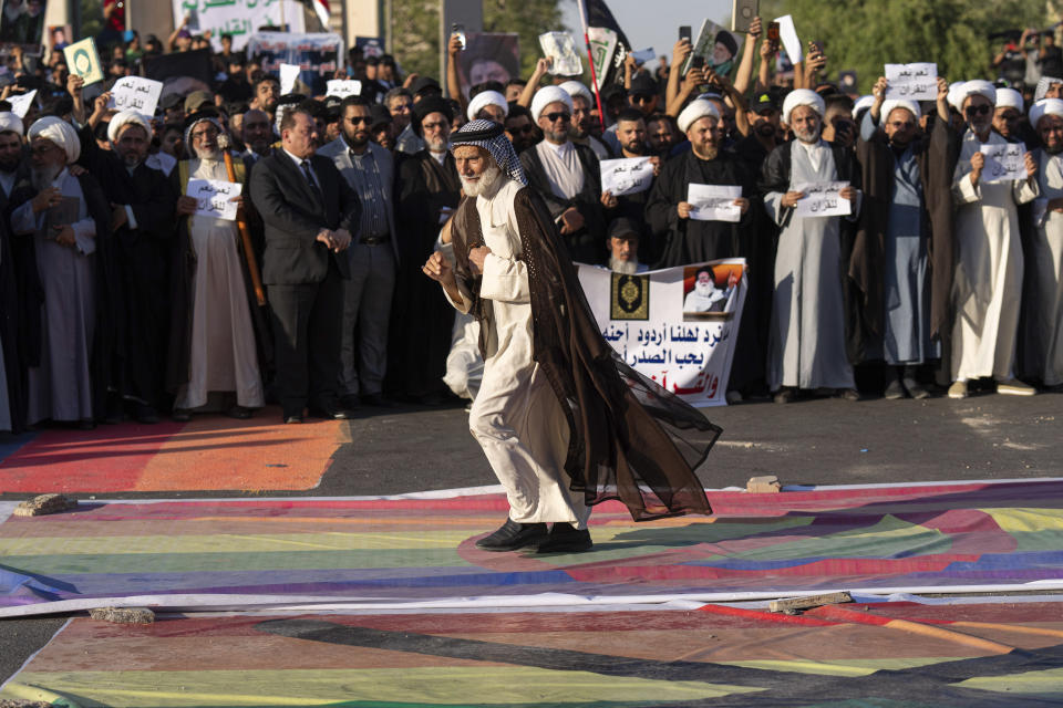 Supporters of Shiite Muslim leader Moqtada Sadr steps on a LGBTQ+ rainbow flag in front of the Swedish embassy in Baghdad in response to the burning of Quran in Sweden, Baghdad, Iraq, Friday, June. 30, 2023. (AP Photo/Hadi Mizban)