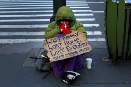 A homeless woman sits bundled against the cold as she begs for handouts on East 42nd Street in the Manhattan borough of New York City, January 4, 2016. REUTERS/Mike Segar