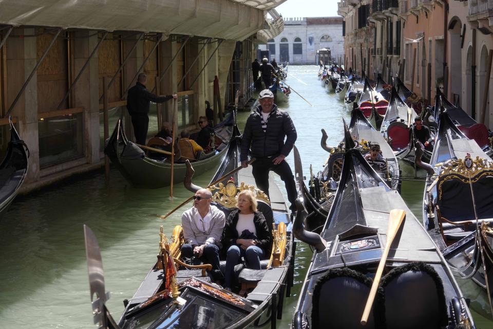 Tourists enjoy a ride on gondolas in Venice, Italy, Thursday, April 25, 2024. The fragile lagoon city of Venice begins a pilot program Thursday to charge daytrippers a 5 euro entry fee that authorities hope will discourage tourists from arriving on peak days. (AP Photo/Luca Bruno)