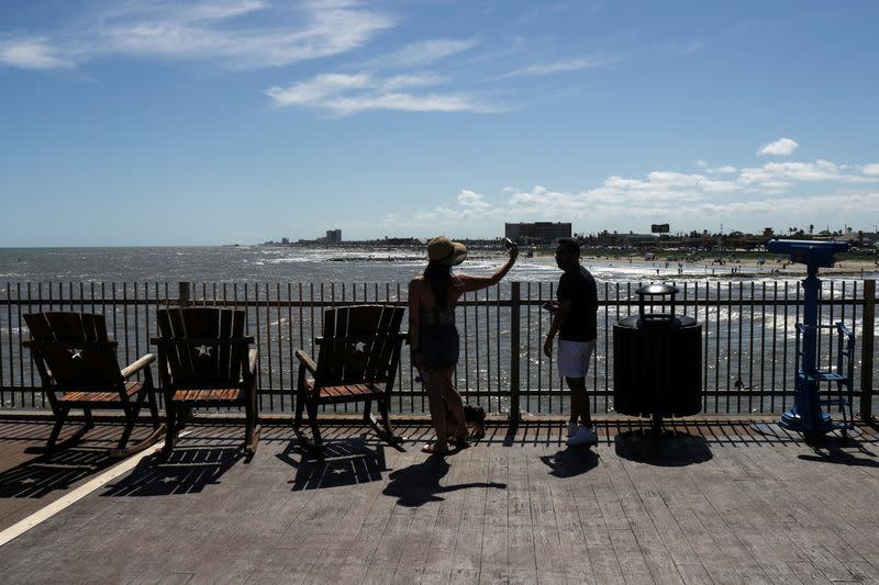 Couple take photographs from pier after partial-reopening of economy during coronavirus disease pandemic in Galveston, Texas