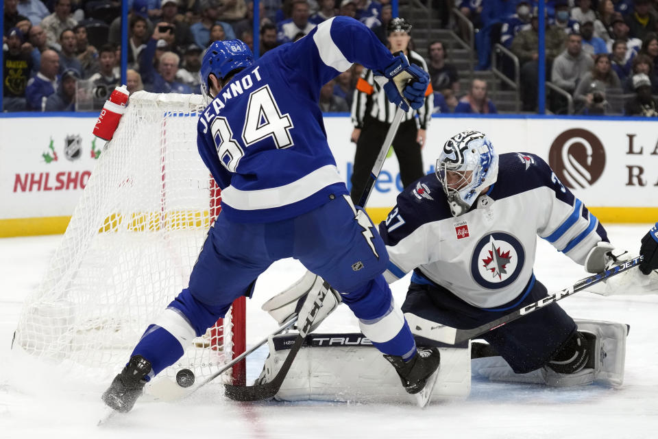 Winnipeg Jets goaltender Connor Hellebuyck (37) makes a stick save on a shot by Tampa Bay Lightning left wing Tanner Jeannot (84) during the second period of an NHL hockey game Wednesday, Nov. 22, 2023, in Tampa, Fla. (AP Photo/Chris O'Meara)